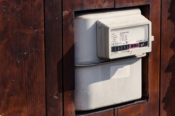 Gas meter for natural gas consumption installed inside a wooden fence at the exterior of a home