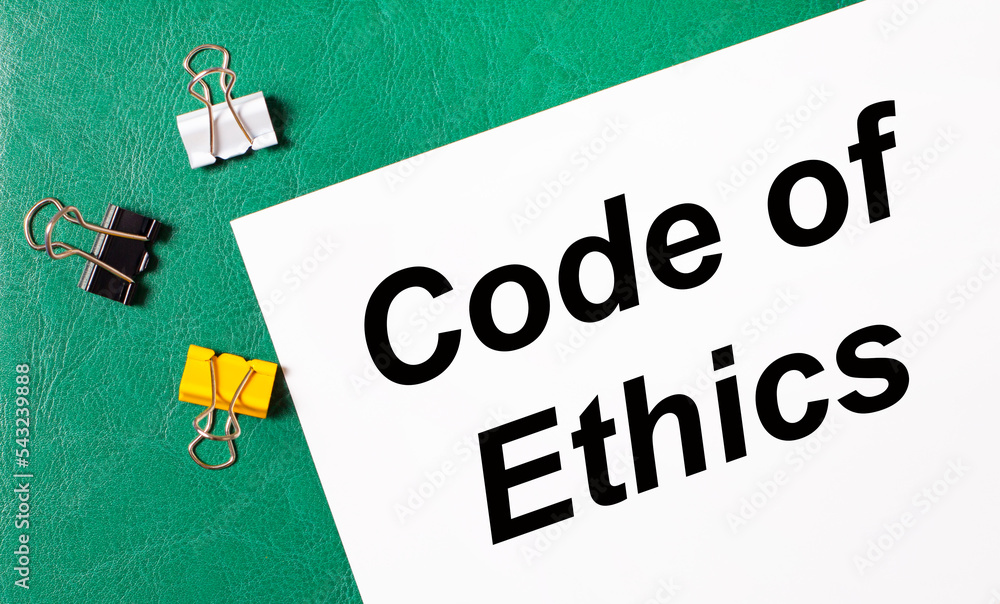 Poster multi-colored paper clips and a sheet of paper with the text code of ethics on a green notepad.
