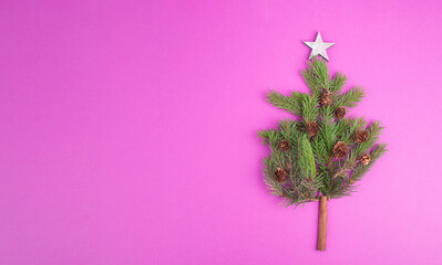 Christmas tree made from fir branches, pine cones and a cinnamon stick as the trunk, pink greeting...