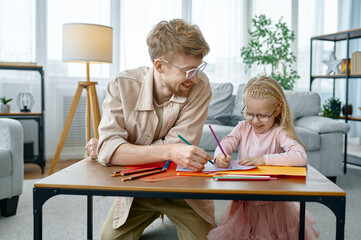 Fototapeta premium Happy father and daughter drawing sitting at desk table