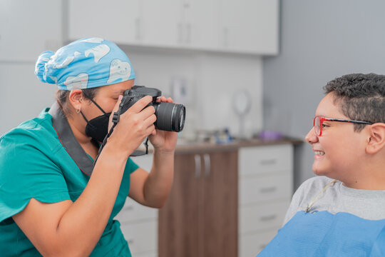 Hispanic female dentist photographing teeth of boy in clinic