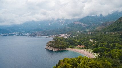 Fototapeta na wymiar Historical part of Montenegro seaside is beautiful and romantic place of Sveti Stefan with long bridge heading to the old town standing on rock in sea. Wonderful landmark of Crna gora with beach, sea