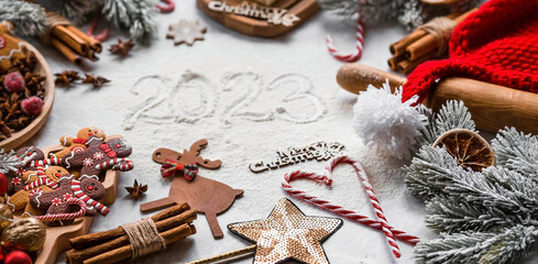 Happy New Year 2023. Banner with kitchen utensils, Christmas decorations, cinnamon, gingerbread and spruce on a marble background. A greeting card for Christmas. The concept of cafes and restaurants.