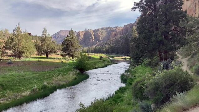 The peaceful Crooked River in stunning Smith Rock State Park. Red rock cliffs and bright green grass and trees surround - Nr Terrebonne, Oregon, USA