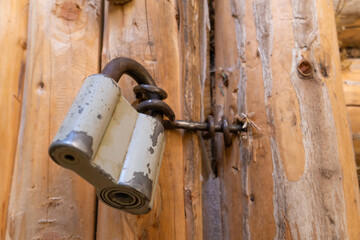 Close-up of a barn lock on wooden rustic doors of a log house.