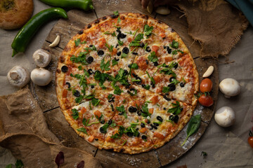 Traditional italian food. Delicious fresh pizza with cheese,  and olives and tomatoes on wooden background with ingredients, flat lay.