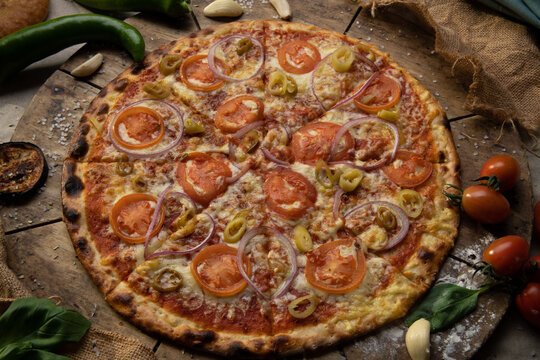 Traditional italian food. Delicious fresh pizza with cheese, tomatoes and onion on wooden background with ingredients, flat lay.