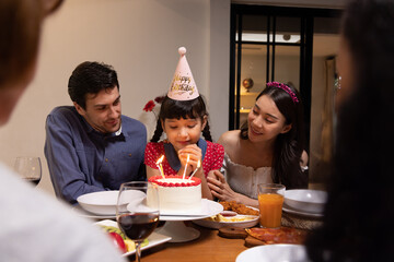 Daughter has a birthday party and is about to blow out candles with happy family - Powered by Adobe