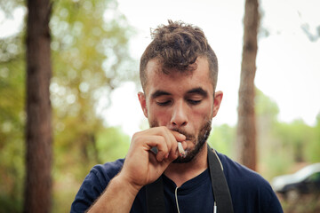 Close-up of a man smoking a marijuana cigarette in a forest