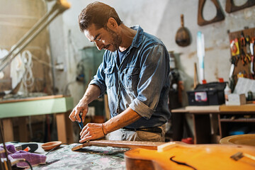 A luthier adjusts the truss rod of a semi-acoustic guitar in his workshop - obrazy, fototapety, plakaty