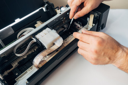 Maintenance and repair of printers. Master's hands with screwdriver. Background. Urgent repair of office equipment at home or in office..