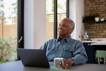 Happy senior male at home using a laptop for personal finances