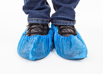 Blue medical shoe covers are worn over shoes on white background, hygiene and cleanliness in medical institutions.	
