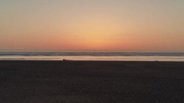Golden hour clear sky sunset over the Pacific Ocean from a sandy beach - timelapse