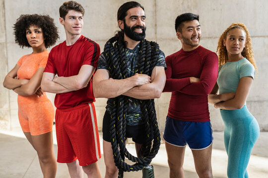Front view of confident multiracial group of people and man with orthopedic leg exercising with battle rope. Fitness concept