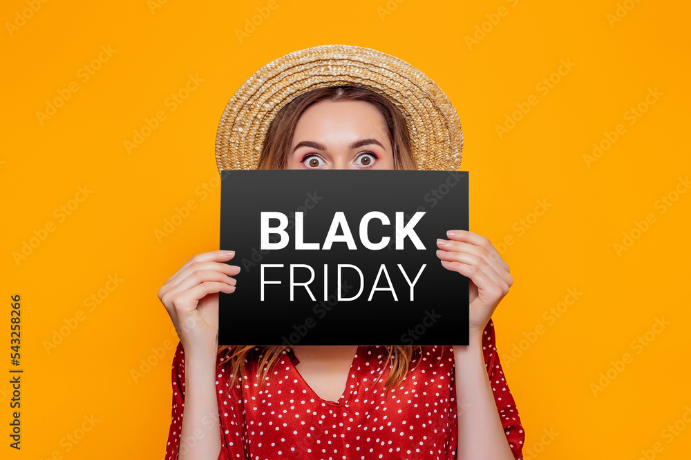 Wall mural woman holding paper poster with black friday isolated on an orange studio background