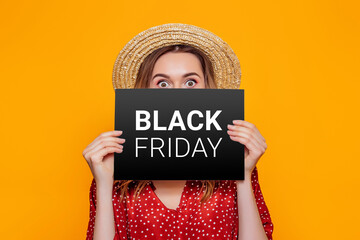 woman holding paper poster with black friday isolated on an orange studio background