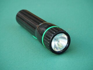 A simple handheld flashlight on a green background. Camping and hiking equipment