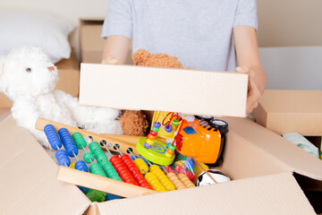 Young volunteer collecting donations for charity indoors. Teenager hand taking cardboard box....