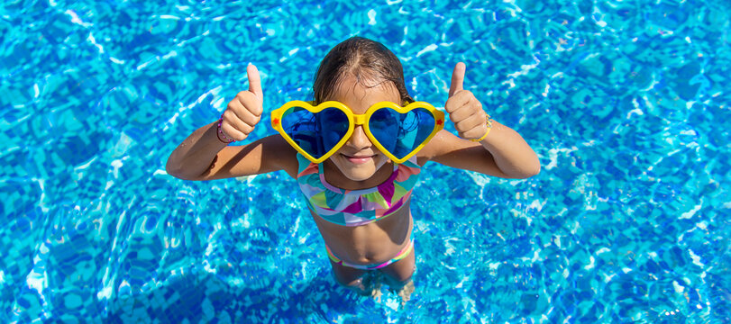 Child in the pool wearing big glasses. Selective focus.