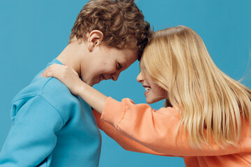 cute, joyful, loving children of school age stand on a blue background and gently hug each other.