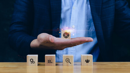 Concept of business planning strategy, hand choose the wooden cube block with icon aiming goal icon...