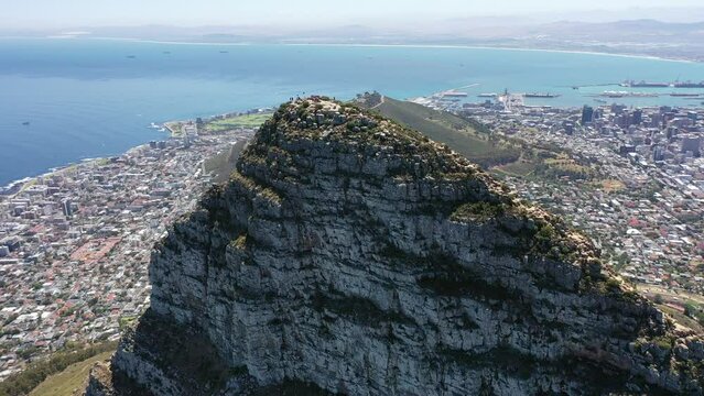 aerial video view - flying around the peak of Lion's Head mountain in Cape Town, South Africa, with a view of Downtown Cape Town,  Seaport, Camps Bay and Robben Island - K4 movie 