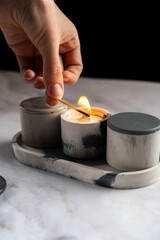 female hand sets fire to soy wax candles, handmade, space for text 
