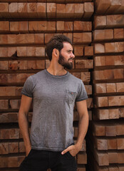 Caucasian bearded man in profile with hands in pockets. Stylish handsome young man dressed casual. Wood background.