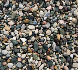 Pattern and texture of small pebbles of different colors in the mountains, texture for a background with soft lighting