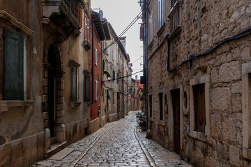 Old town alley in the Croatian town of Rovinj with old residential building fronts and freely laid power cables