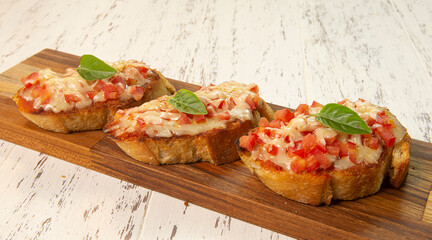 Deliciosas brusquetas com pão italiano, molho de tomate temperado, queijo mussarela e parmesão...