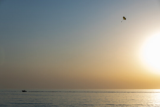 Speedboat pulling parasail at sunset