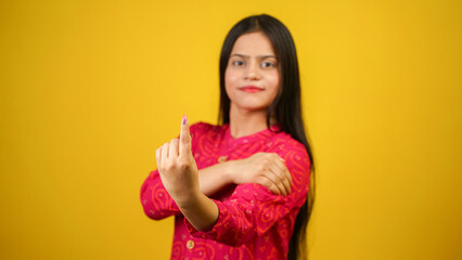 Young Indian girl showing finger after voting, cheerful girl isolated over yellow background
