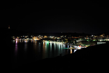 Night city with lights on the background of mountains.