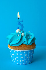 Birthday cupcake with with candles 5 five on a blue background. Cake with blue cream. Festive dessert and congratulations.