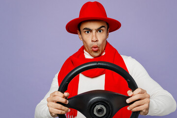 Young shocked middle eastern man 20s he wearing white turtleneck red hat scarf hold steering wheel driving car look camera isolated on plain pastel light purple background. People lifestyle concept.