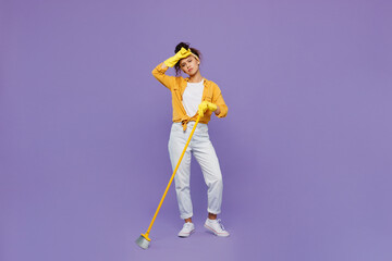 Full body young housekeeper woman wear yellow shirt tidy up hold use broom sweeping brush put hand...