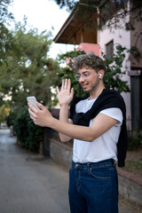 young and modern man video chatting with his phone on the street, portrait and outdoor photography