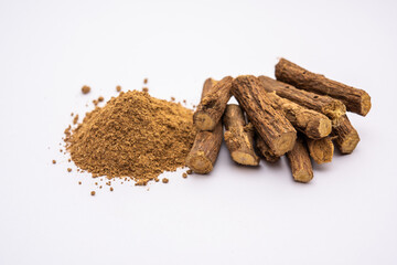 Ayurvedic Mulethi or Liquorice root stick or jeshthamadh powder served in a bowl over moody background