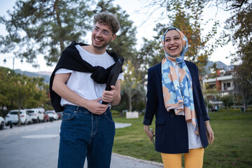 young businessman and hijab woman walking in modern city street laughing