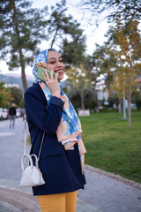 young woman in turban talking on the phone in the city street