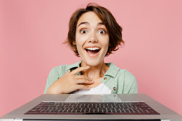 Close up excited shocked fun young IT woman 20s she wearing green shirt white t-shirt holding use...