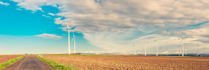 Panorama Web banner of Wind Turbines On Field on moody blue sky background. Group of windmills for electric power production in the agriculture field in autumn. energy saving concept 