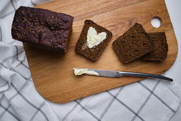 Soft slices of delicious bread with butter on a wooden board. Dark grain bread for breakfast. Fragrant pastries