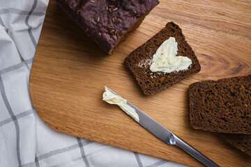 Soft slices of delicious bread with butter on a wooden board. Dark grain bread for breakfast. Fragrant pastries