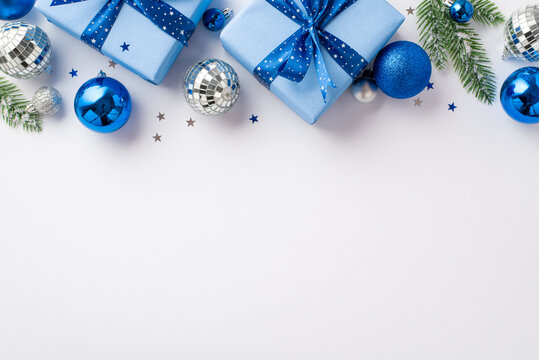 New Year decor concept. Top view photo of blue white and silver baubles disco balls gift boxes with ribbon bows pine branches and confetti on isolated white background with empty space