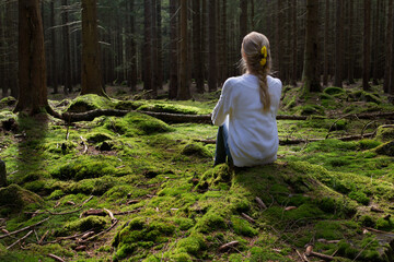 Woman sitting in green forest enjoys the silence and beauty of nature.