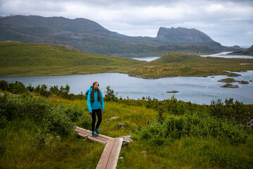 Fototapeta na wymiar girl with a backpack hiking to the famous kvalvika beach on lofoten islands, norway; hiking in the norwegian fjords, rugged landscape of northern norway
