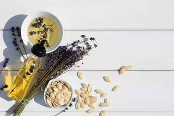 Healthy cooking oil, lavender flowers and pumpkin seeds on white wooden table, flat lay. Space for text